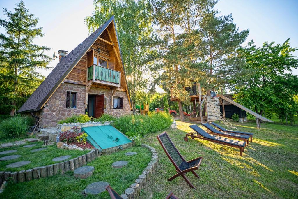 Rustic cottage JARILO, an oasis of peace in nature في Ležimir: كابينة خشب بها مسبح ومنزل