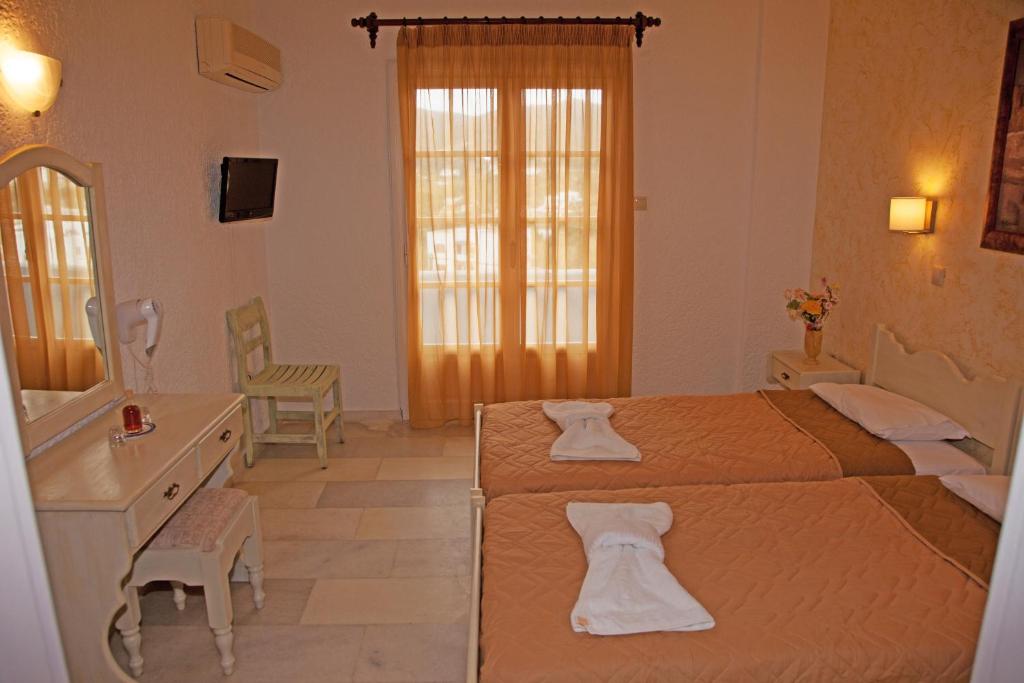a bedroom with two beds and a vanity and a mirror at St.George Valsamitis in Katapola