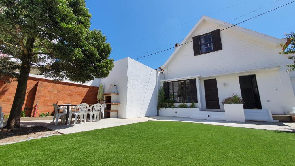 een wit huis met een tafel en stoelen in een tuin bij The Beach House in Praia da Barra