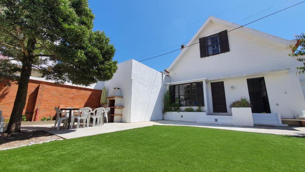 a white house with a table and chairs in a yard at The Beach House in Praia da Barra