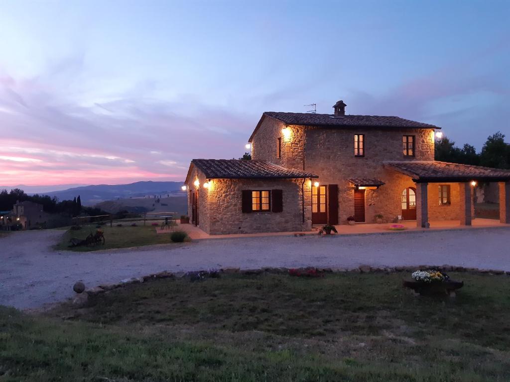 a large stone house with lights on it at dusk at Agriturismo Poggio Ridulfo in Volterra