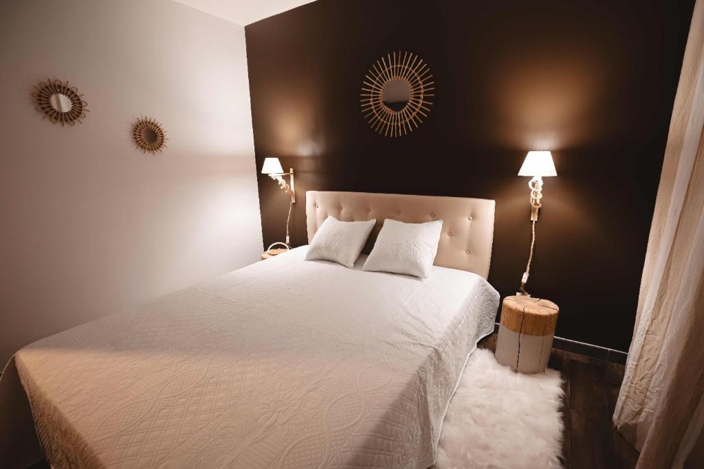 a bedroom with a white bed with two lamps and a mirror at Appartement et Garage au Cœur de l'Isle in LʼIsle-sur-la-Sorgue