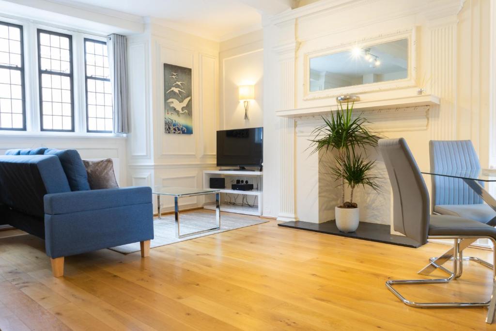 a living room with a blue couch and a fireplace at Executive City Centre Apartment with Gated Parking and Stylish Rooms includes Privacy and Space with Luxury Feel plus Courtyard Garden in Amazing Location and Very Highly Rated in Peterborough