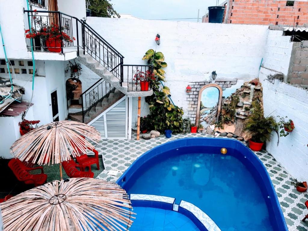 a swimming pool with two umbrellas next to a building at Hostal Solsticio Guajiro in Ríohacha