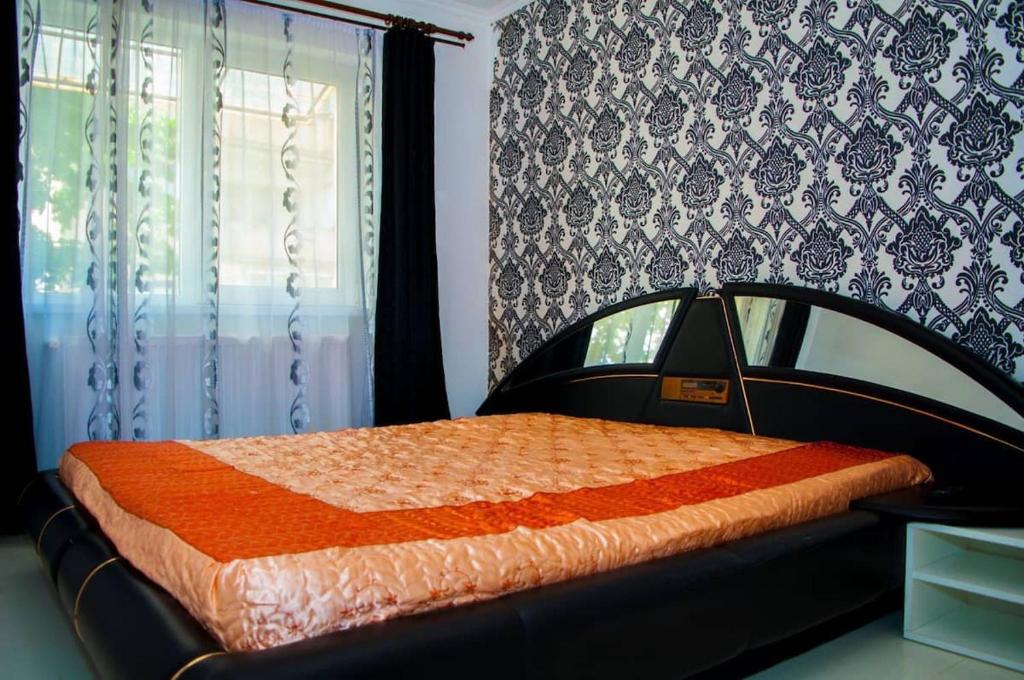 a bedroom with a bed with an orange comforter and a window at Apartament 2 camere in Haţeg