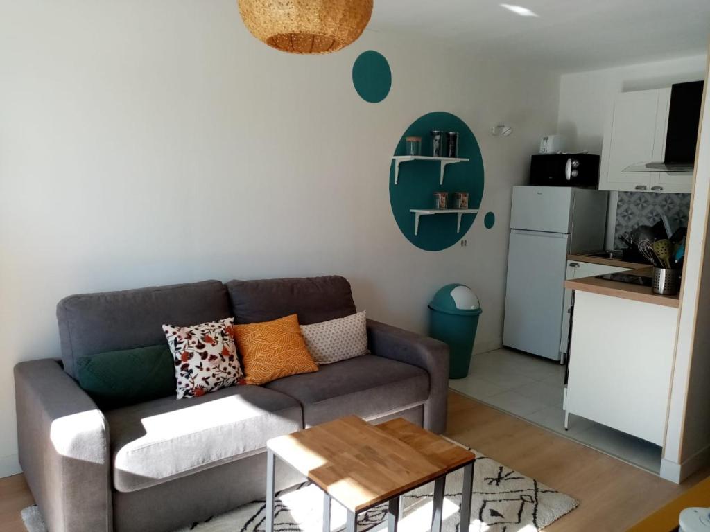 ein Wohnzimmer mit einem Sofa und einer Küche in der Unterkunft Appartement cocoon à Courseulles sur Mer in Courseulles-sur-Mer