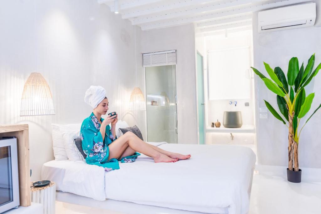 Anastasia's Visage II Stylish Accommodation Rooms City Center Mykonos في مدينة ميكونوس: امرأة تجلس على أريكة بيضاء لالتقاط صورة