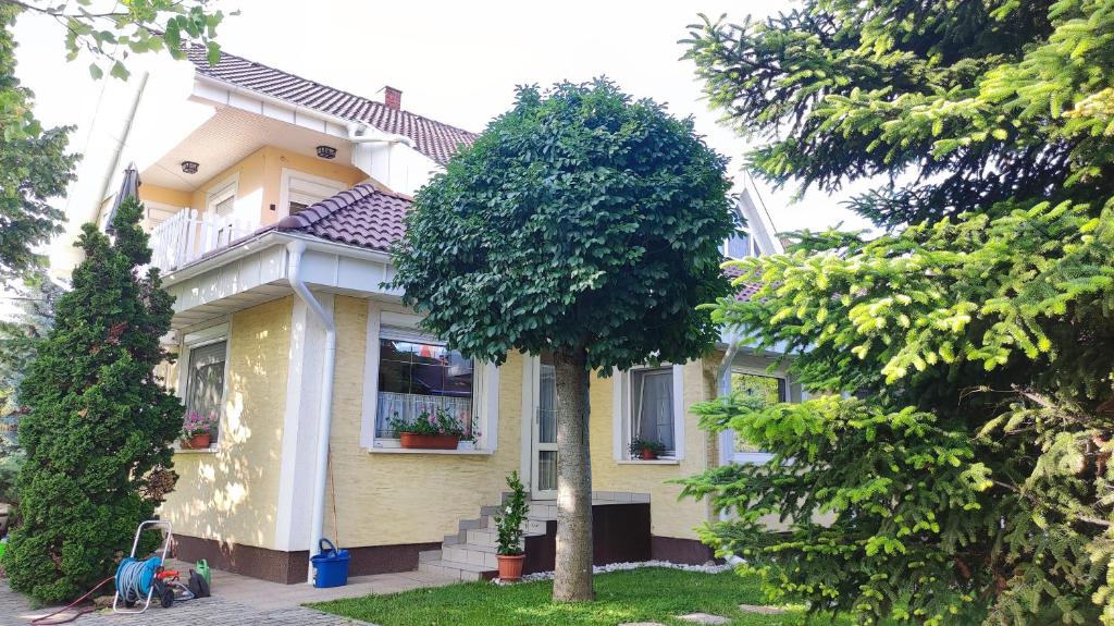 une maison jaune avec un arbre devant elle dans l'établissement Oázis Apartman, à Szántód