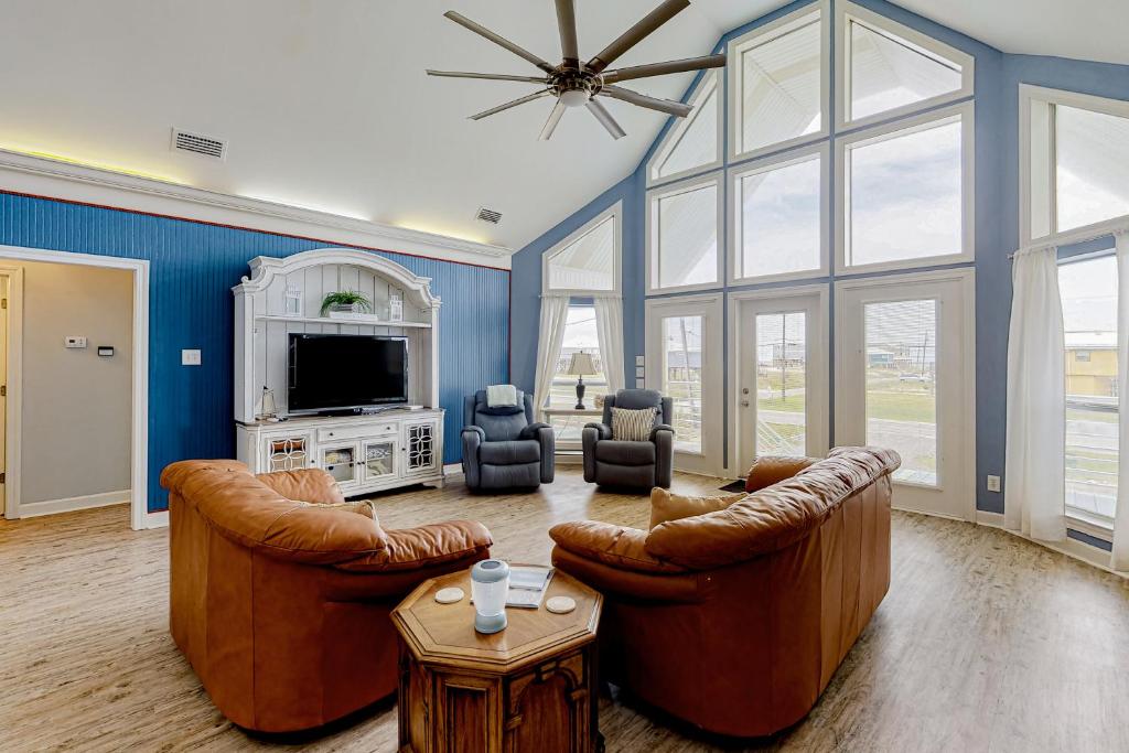 a living room with two leather chairs and a tv at Shore Beats Work in Dauphin Island