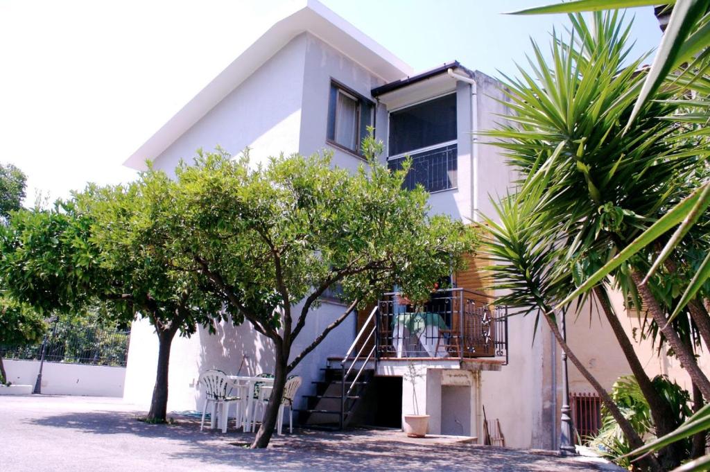 una casa bianca con balcone e alcuni alberi di B&B Il Grillo a Santa Maria del Cedro