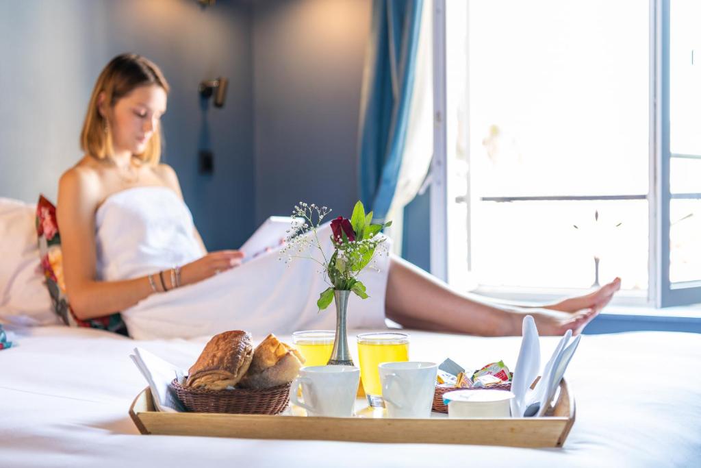a woman sitting on a bed with a tray of food at Boutique Hotel Nice Côte d'azur in Nice
