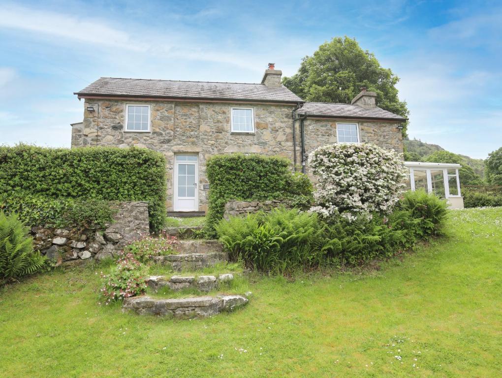 une ancienne maison en pierre avec un jardin en face de celle-ci dans l'établissement Fron Fawr, à Nefyn