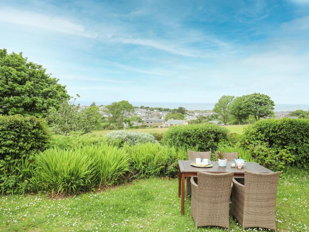 a table and chairs in a garden with a view at Fron Fawr in Nefyn