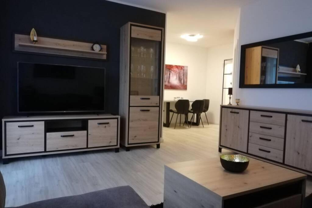 a living room with a flat screen tv and a large entertainment center at Ferienwohnung am Kurwald in Bad Lippspringe in Bad Lippspringe