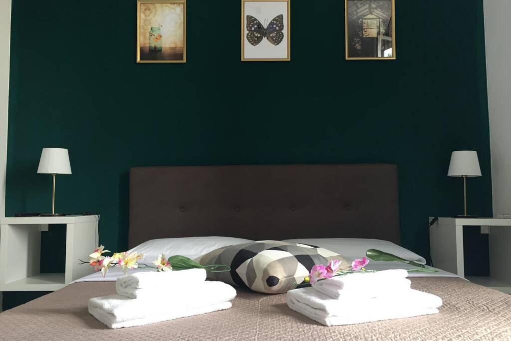 a bedroom with a green wall and a bed with towels at Bologna Central Apartments - Indipendenza 43 in Bologna