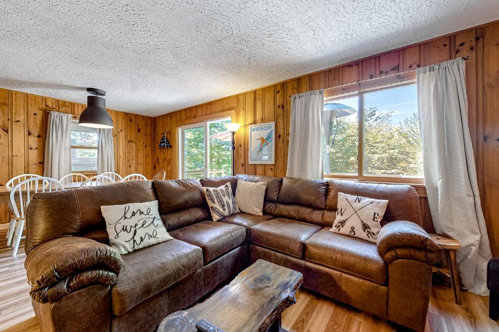 sala de estar con sofá de cuero marrón y mesa en Rockhouse Mountain Retreat, en Conway