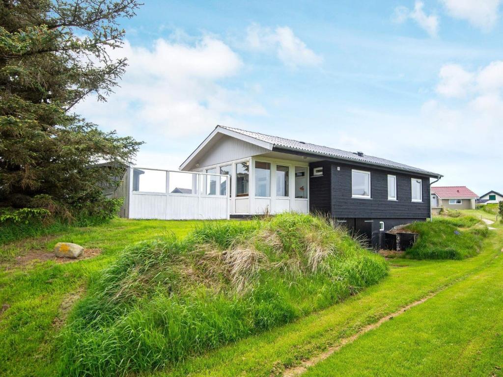 a small house on a hill with a grassy yard at 6 person holiday home in R m in Bolilmark