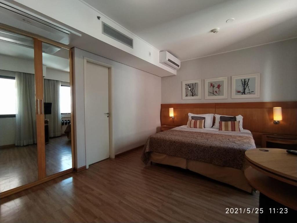 Un dormitorio con una cama y una mesa. en Flat Moema Rouxinol, en São Paulo