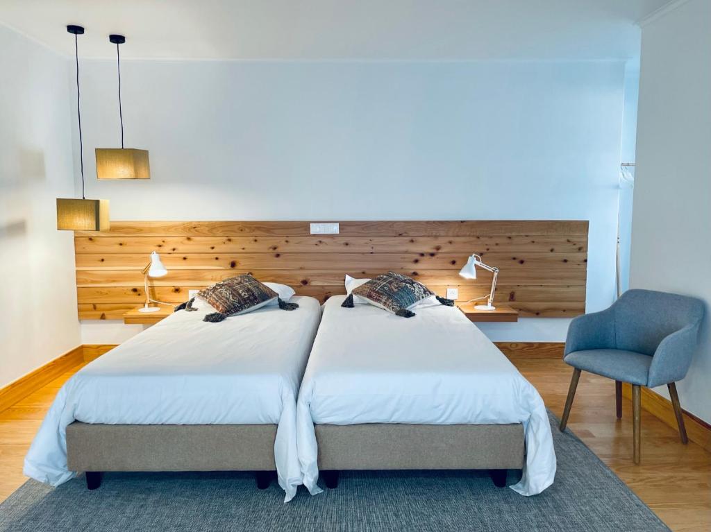 um quarto com 2 camas e uma cadeira azul em PDL Green House em Ponta Delgada