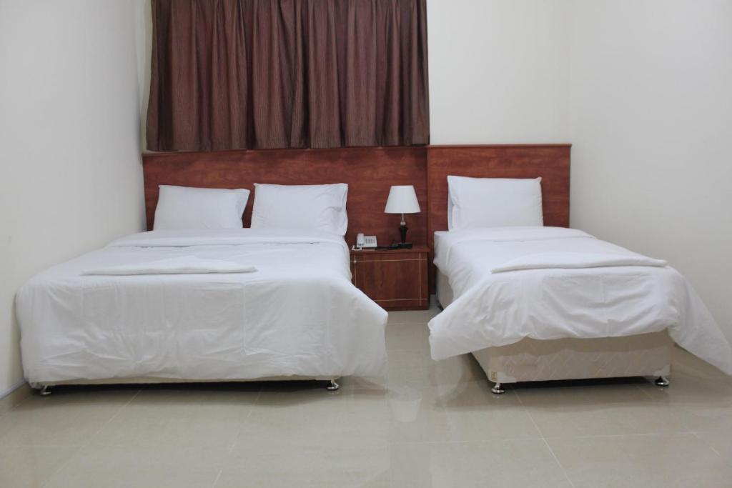 a bedroom with two beds with white sheets at Africana Hotel in Dubai