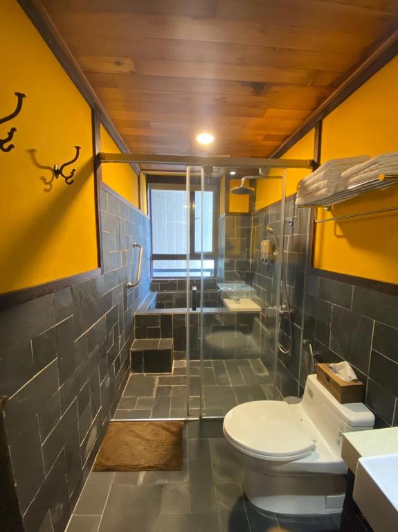 a bathroom with a toilet and a shower with yellow walls at Yong Guan in Yuchi