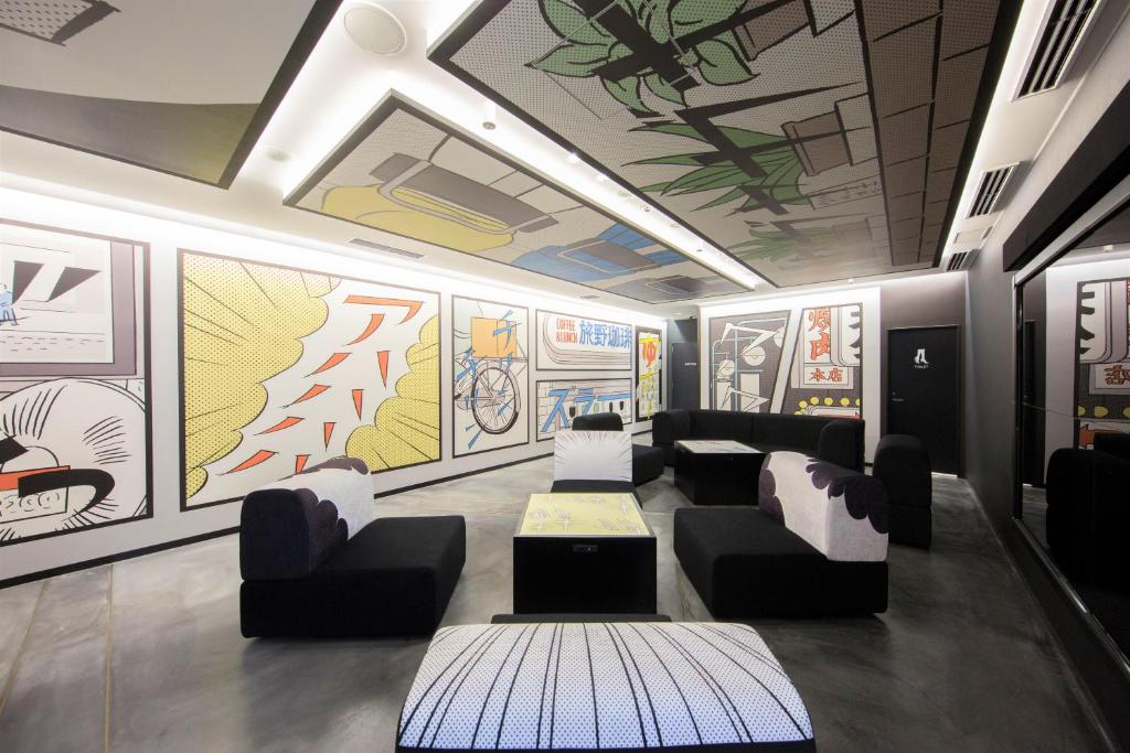 una sala de espera con sofás, mesas y pinturas en las paredes en HOTEL TAVINOS Hamamatsucho, en Tokio
