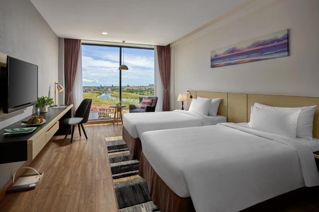 ドンホイにあるKhách sạn SAM Quảng Bìnhのベッド2台とデスクが備わるホテルルームです。