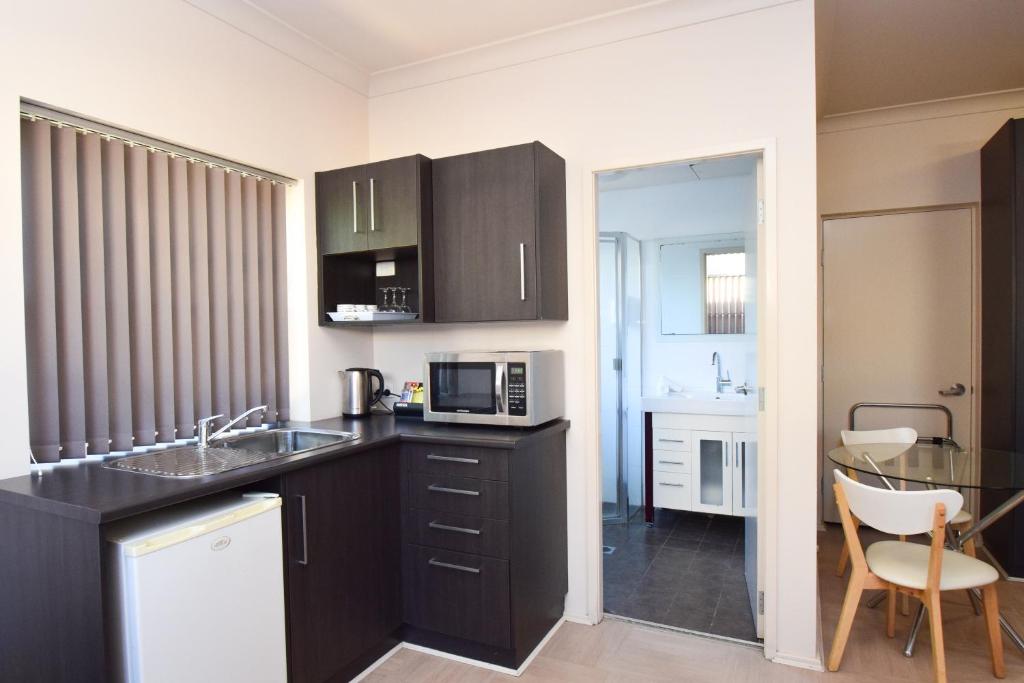 a kitchen with a sink and a microwave at Station Hotel Motel Kurri in Kurri Kurri