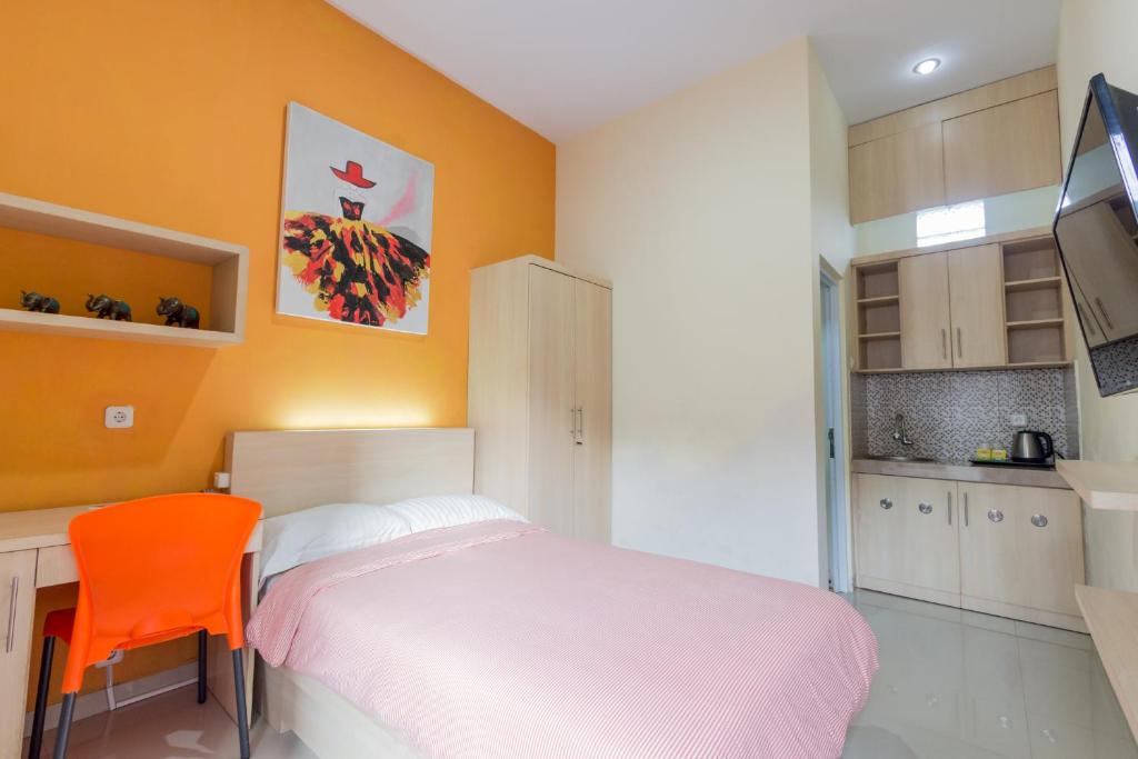 a bedroom with a bed and a orange chair at Omah Ayu Mendiro in Ngemplak