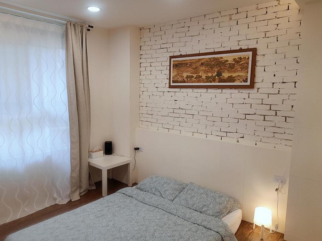 a bedroom with a bed and a brick wall at 光鹿旅人短期月租出租 in Tanzi