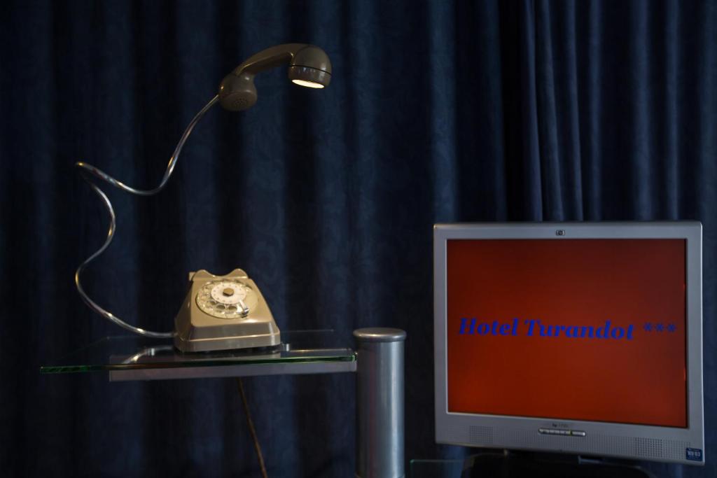 a desk with a computer monitor and a lamp and a phone at Hotel Turandot in Torre del Lago Puccini