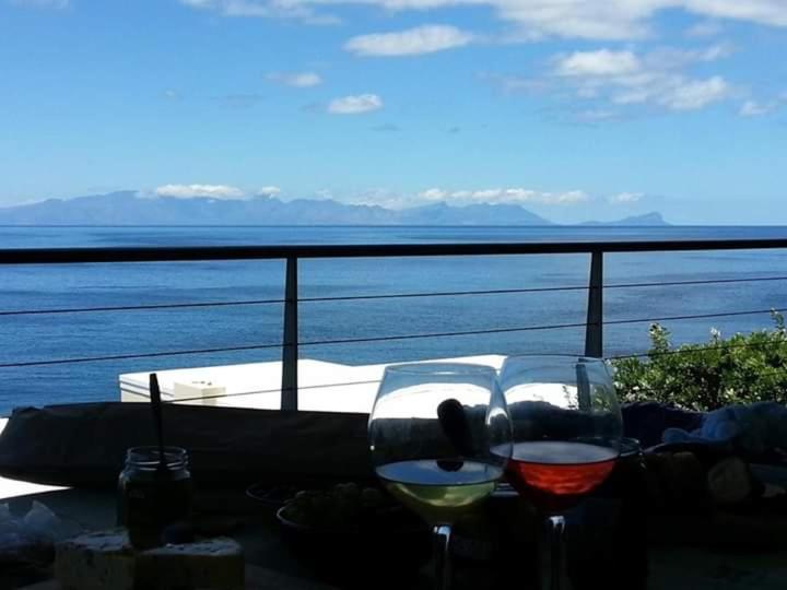 two glasses of wine sitting on a table overlooking the water at Quarterdeck Holiday Apartment in Simonʼs Town