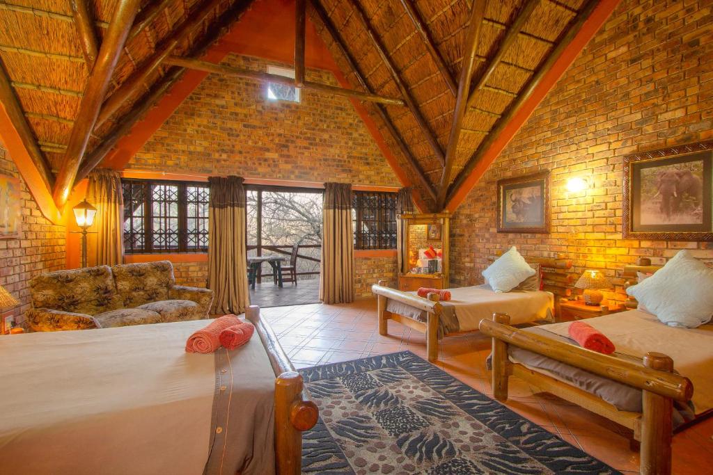 a bedroom with two beds in a room with a brick wall at SERENITY Du Bois Lodge in Marloth Park