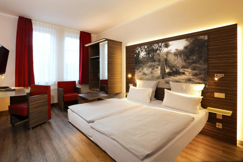 a bedroom with a large white bed and a desk at Gieschens Hotel in Achim
