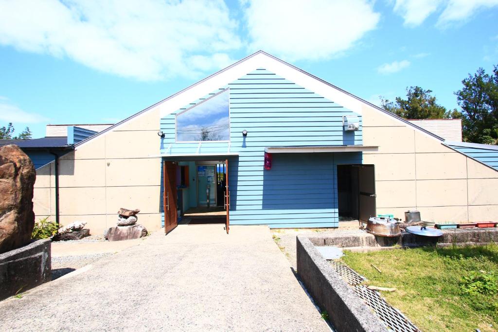 a blue and white house with a driveway at Rest and Lodge Syou in Amami