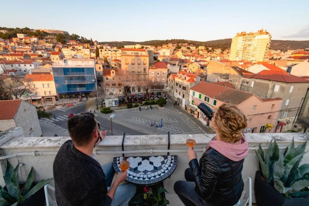 un hombre y una mujer sentados en una cornisa con vistas a una ciudad en The Spot - Rooftop in the city centre + Parking en Šibenik