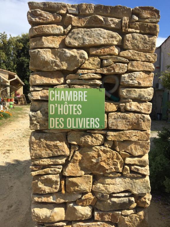 a sign on the side of a stone wall at chambre d’hôtes des oliviers in La Roque-sur-Cèze
