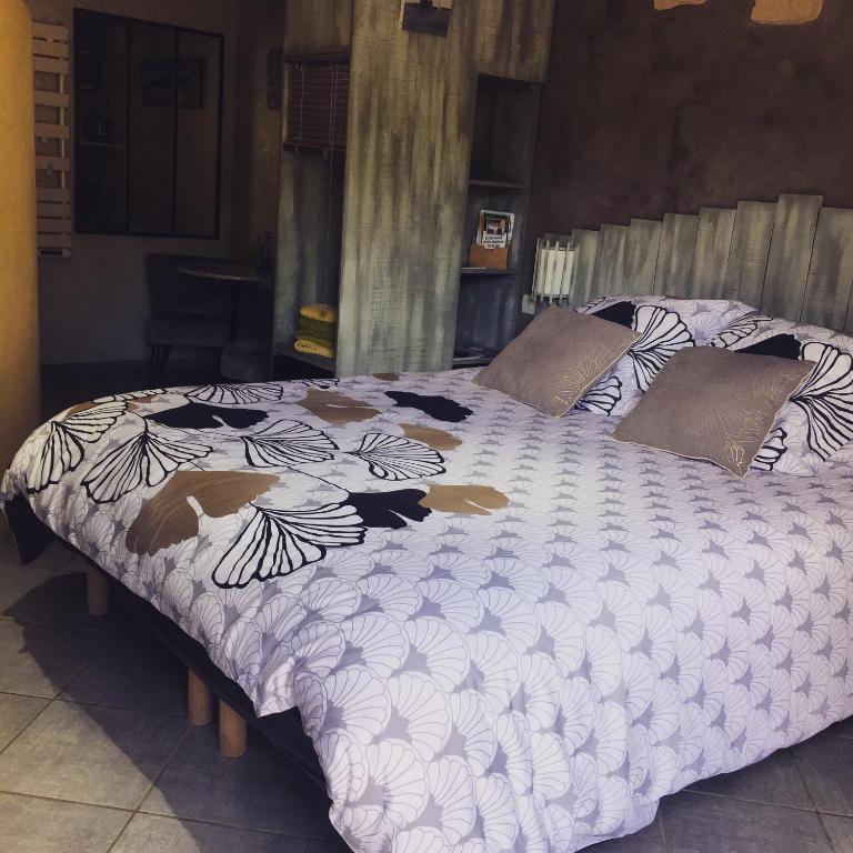 a bed with a white comforter with flowers on it at chambre d’hôtes des oliviers in La Roque-sur-Cèze