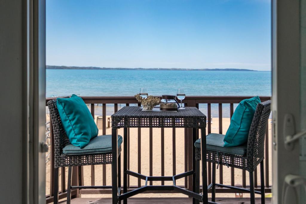 a table and chairs on a balcony with the ocean at New Listing Beach Bliss 211! Stunning bay view in Traverse City