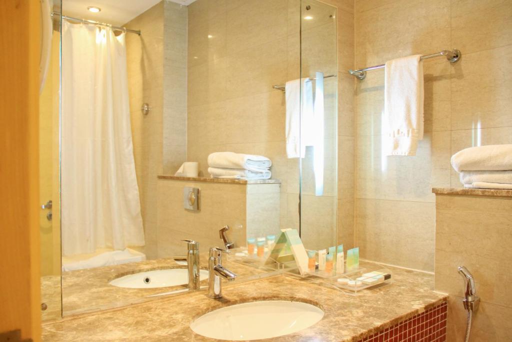 La salle de bains est pourvue d'un lavabo et d'une douche. dans l'établissement The Leela Hotel, à Dubaï