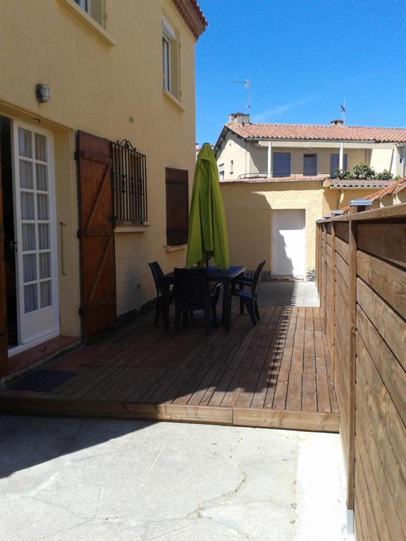 un patio avec une table et un parasol vert dans l'établissement La Luciole, à Canet