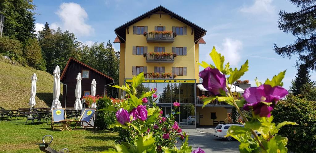 un edificio giallo con dei fiori davanti di Hotel Zarja a Hočko Pohorje