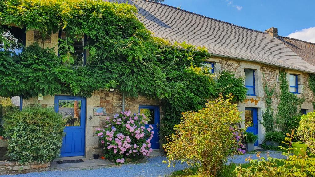 una antigua casa de piedra con puertas azules y flores en Les Floralis, en La Grée-Saint-Laurent