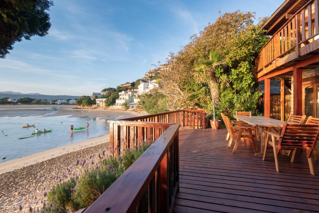 a wooden deck with a table and chairs on the beach at Paquita Self Catering Holiday House in Knysna