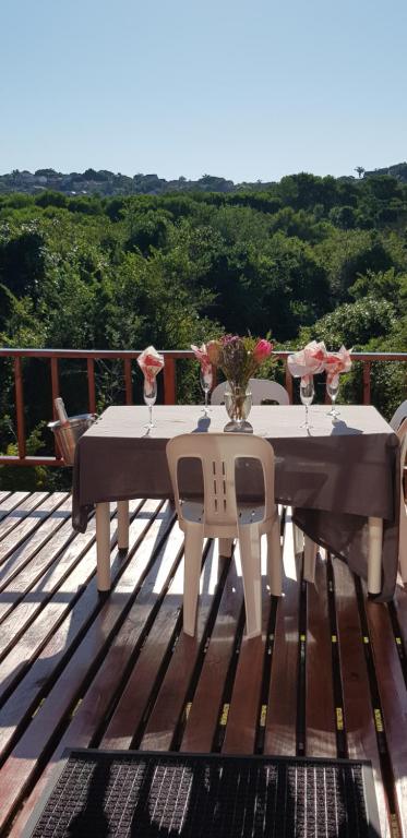 a white table with chairs and flowers on a deck at Home2Home Protea Cottage in Port Elizabeth