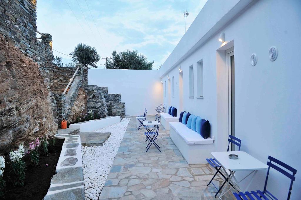 a patio with blue chairs and a white building at Beba's Studios in Batsi