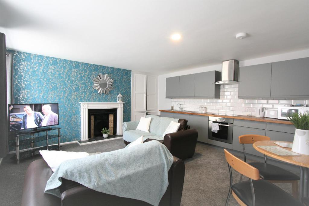 a kitchen and a living room with a couch and a tv at Albion Street Serviced Apartments in Cheltenham