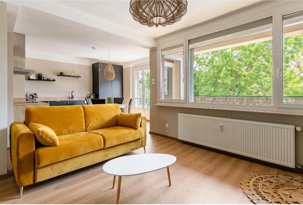 - un salon avec un canapé jaune et une table dans l'établissement L'austerlitz, T2 au coeur de Strasbourg, à Strasbourg