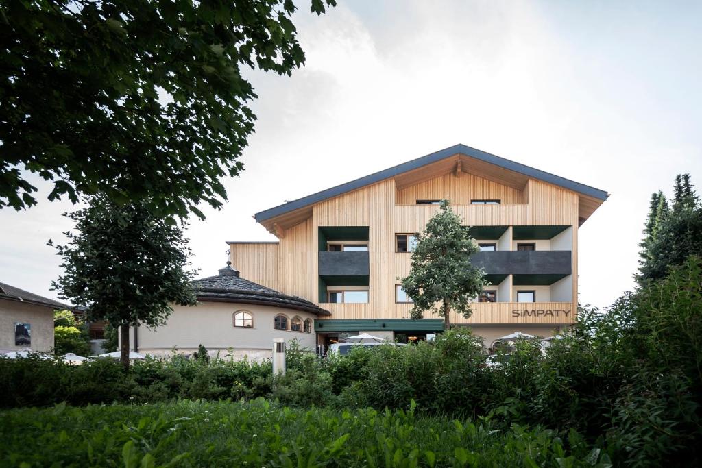 ein Apartmenthaus mit einem Holzdach in der Unterkunft Hotel Simpaty in Toblach