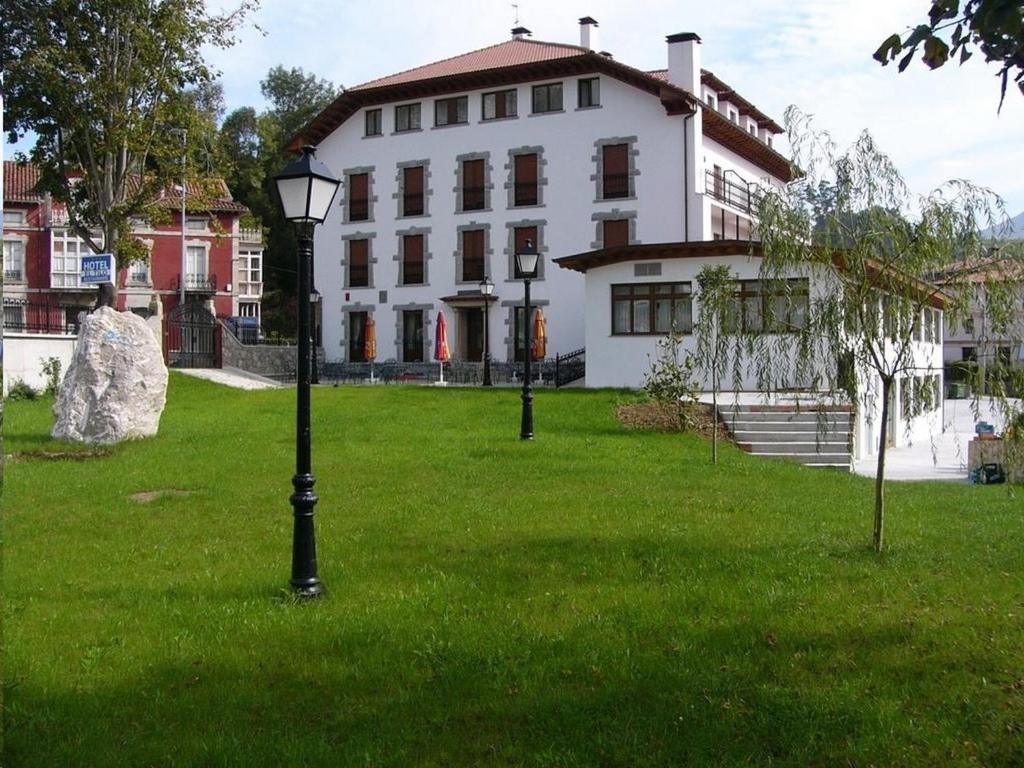 un gran edificio blanco con un césped verde delante de él en Hotel El Tilo, en Panes